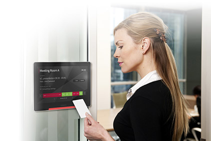 Woman looking at a card in front of a meeting room booking system